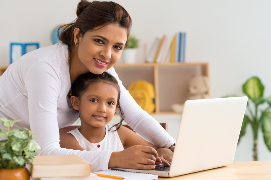 Girl reading on computer with mother